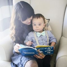 a woman is holding a baby and reading a book