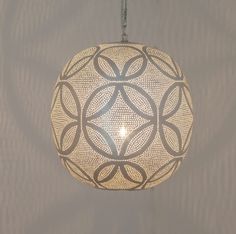 a light fixture hanging from a ceiling in the shape of a circular object with an intricate design on it