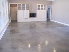 an empty living room with white cabinets and gray flooring is pictured in this image