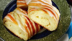 two glazed donuts on a blue plate with white glaze and orange icing