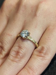 a close up of a person's hand with a diamond ring on their finger