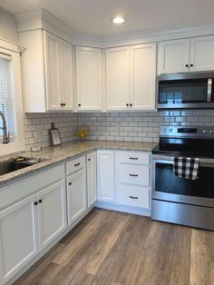 a kitchen with white cabinets and stainless steel appliances