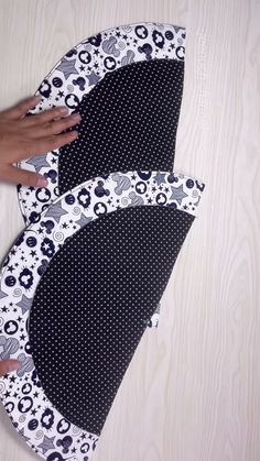 two pieces of black and white fabric with polka dots on them are being cut out