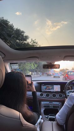 two people sitting in the driver's seat of a car looking at their cell phones