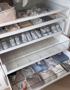 an open cabinet filled with baby clothes and shoes