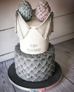 a cake with two cakes on top of it and the words baby coming written in white