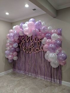 balloons and streamers decorate the entrance to a room with purple drapes on it