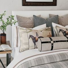 a bed with two pillows and some pictures on the wall next to it, along with a plant