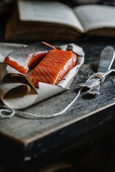 two pieces of fish sitting on top of a wooden table next to an open book