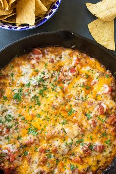 a skillet filled with mexican food next to tortilla chips