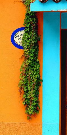 an orange and blue building with a clock on it's face, hanging from the side