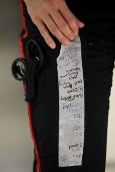 a person holding onto a piece of paper with writing on it that is attached to their pants