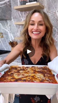 a woman is holding a large pan of food