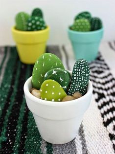 small green and white rocks in a bowl on a black and white table cloth next to potted plants