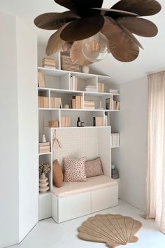 a living room with white walls and shelves filled with books, pillows and other items