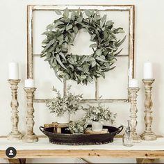 a wreath on top of a mantle next to candles