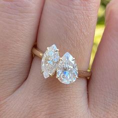 a woman's hand with two engagement rings on her fingers, one has an oval diamond