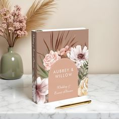 a wedding album sitting on top of a table next to a vase with flowers