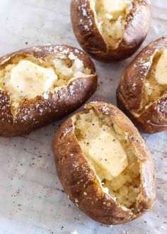 four baked potatoes with butter and seasoning sprinkled on them