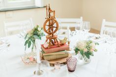 a table topped with books and vases filled with flowers on top of each other