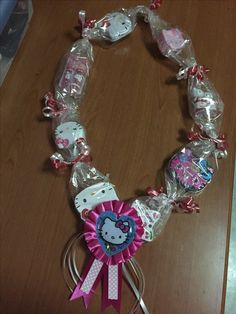 hello kitty lollipop bracelet with pink ribbon and bow on wooden table next to scissors