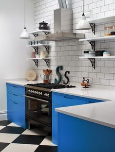 a kitchen with black and white checkered flooring, blue cabinets and an oven