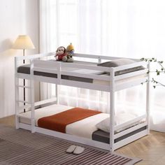 a white bunk bed sitting in a bedroom next to a lamp on a wooden floor