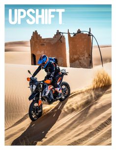 a man riding on the back of a motorcycle down a sandy hill in the desert