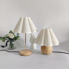 two lamps sitting on top of a table next to a vase with flowers in it