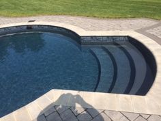 the shadow of a person standing in front of a swimming pool with steps leading up to it