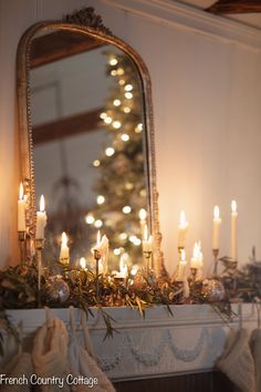 a mantle with candles, stockings and a mirror on it in front of a christmas tree