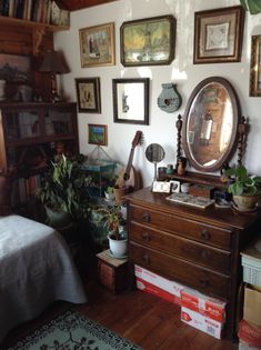 a bedroom with many framed pictures on the wall and a dresser in front of it