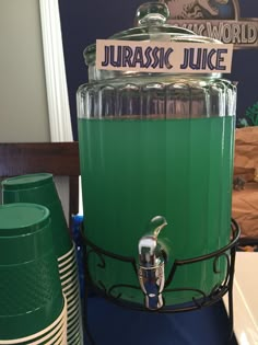 a green juicing machine sitting on top of a table next to stacks of plates