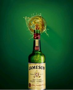 a bottle of jameson on a green background with water splashing from it's top