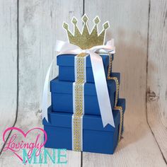 a stack of blue books with a crown on top and ribbon around the edges, sitting against a white wooden background