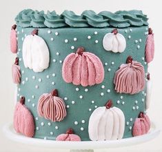 a blue cake with pink and white frosting pumpkins on it's side