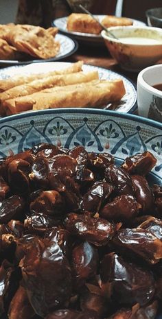 a table topped with plates filled with food next to bowls of dipping sauce and breadsticks