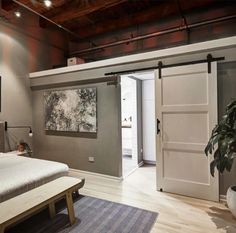 a bed sitting in a bedroom next to a wooden floor and white walls with sliding doors