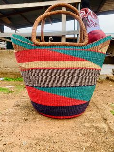 a person sitting on the ground with a large basket in front of them that is made out of woven material