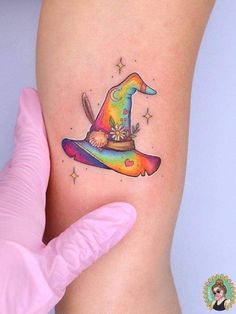 a woman's leg with a colorful tattoo on it and a wizard hat in the middle