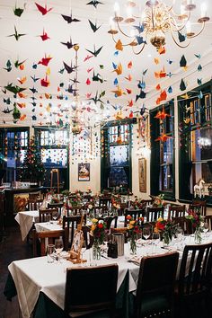 the dining room is decorated with paper cranes hanging from the ceiling and tables covered in white tablecloths