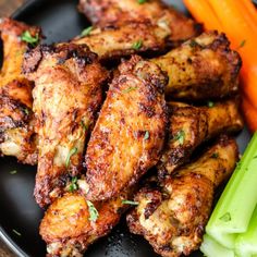 chicken wings with carrots and celery on a black plate