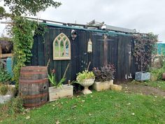 an old wooden shed with potted plants in the yard