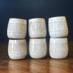 four white ceramic cups sitting on top of a wooden table