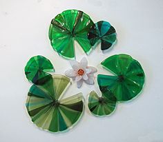 four pieces of green and white glass with flowers in the center on a white surface