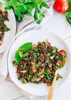 two white plates filled with lentils and garnished with cilantro leaves