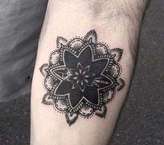 a black and white flower tattoo on the left leg, with an intricate design in the middle