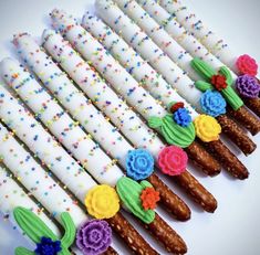 there are many white candles decorated with flowers and icing on the top one is made out of pretzels