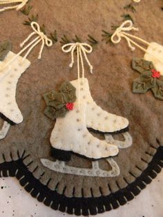 an embroidered christmas ornament with snow boots and holly wreaths hanging from strings