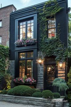 a black house with lots of windows and plants growing on the side of the building